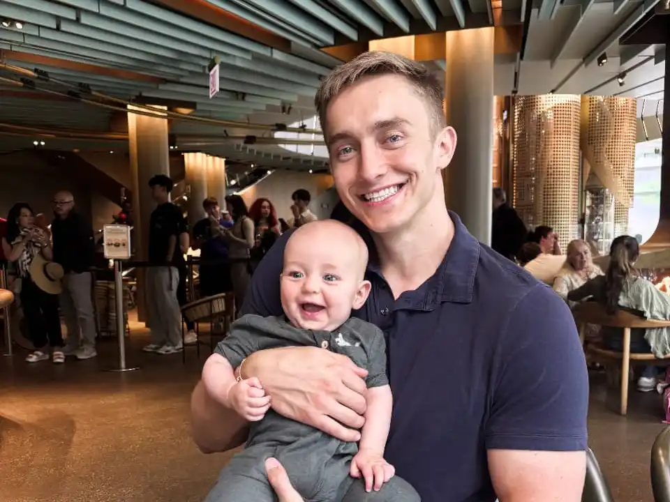 Smiling parent holding a happy baby, symbolizing how warmth and connection nurture emotional well-being and teen mental health.