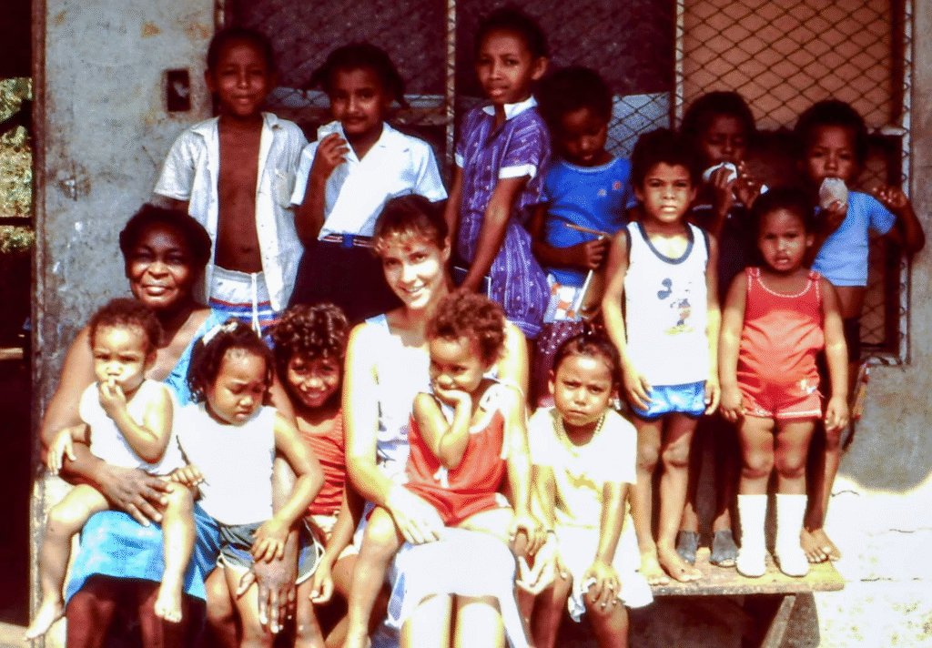 Young woman volunteering in a refugee camp surrounded by children, symbolizing the beginning of a lifelong mission to protect kids